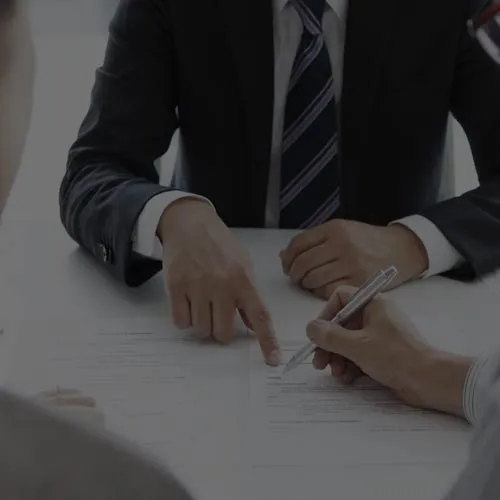 A person in business attire pointing at documents on a table